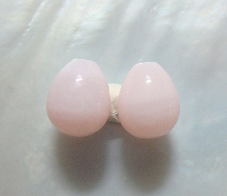Puede incluir: Dos cuentas de vidrio de color rosa p&aacute;lido en forma de l&aacute;grima.
