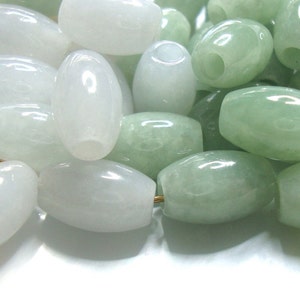 May include: A collection of oval-shaped jade beads in shades of white and green. The beads are smooth and polished, with a subtle sheen.