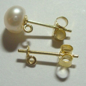 May include: A pair of gold pearl earrings with a white pearl on one side and a gold post and back on the other side.
