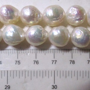 May include: A strand of white pearls with iridescent highlights, measured against a ruler. The pearls are approximately 7.5 mm in diameter.