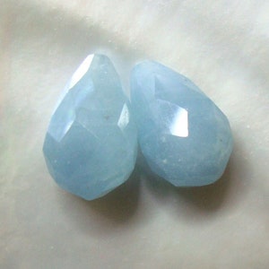 May include: Two light blue faceted teardrop shaped gemstone beads.