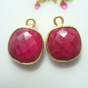 Può includere: Due ciondoli pendenti placcati in oro con pietre preziose quadrate di colore rosso rubino sfaccettate.