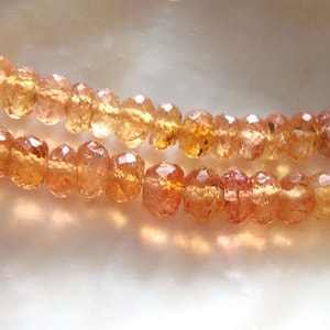 May include: A strand of orange gemstone beads. The beads are faceted and have a translucent appearance.