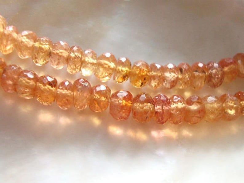 May include: A strand of orange gemstone beads. The beads are faceted and have a translucent appearance.