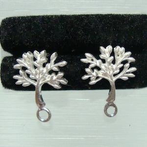 May include: A pair of silver tree-shaped earring charms with a loop at the bottom for attaching to jewelry.