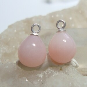 May include: Two pink opal teardrop shaped charms with silver jump rings.