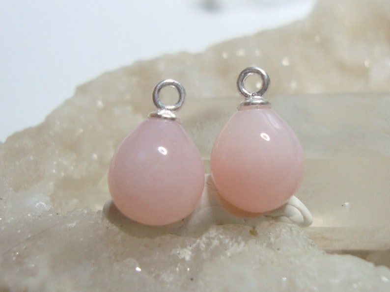 May include: Two pink opal teardrop shaped charms with silver jump rings.