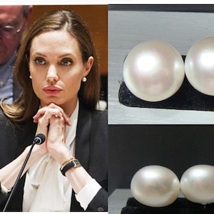 May include: A pair of large, white pearl earrings. The pearls are round and smooth, and they have a high lustre.
