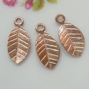 May include: Three gold-toned metal leaf charms with a textured surface. Each charm has a small loop at the top for attaching to jewellery or other crafts.