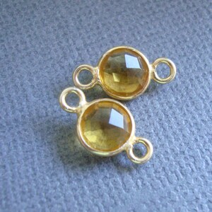 Puede incluir: Dos abalorios conectores de tono dorado con piedras de citrino amarillo facetadas. Cada abalorio tiene dos lazos para sujetar a las joyas.