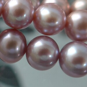 May include: A strand of pink pearls with a high lustre. The pearls are round and smooth, and they are strung together on a clear thread.