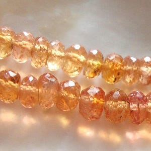 May include: A strand of orange gemstone beads. The beads are faceted and have a translucent appearance.
