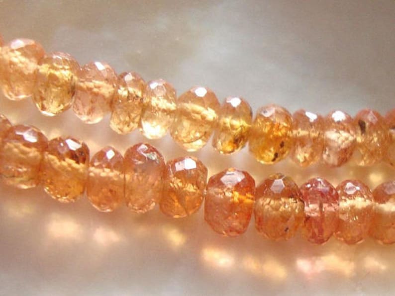 May include: A strand of orange gemstone beads. The beads are faceted and have a translucent appearance.