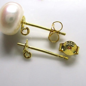 May include: A pair of gold-tone pearl earrings with a white pearl and a post back.