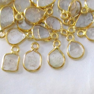 May include: A group of gold-plated, clear glass teardrop and square-shaped charms with a loop for hanging.