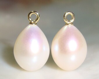 May include: Two pearlescent white teardrop-shaped pearl pendants with gold jump rings.