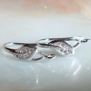 May include: Two silver leaf-shaped earring hooks with clear cubic zirconia stones.
