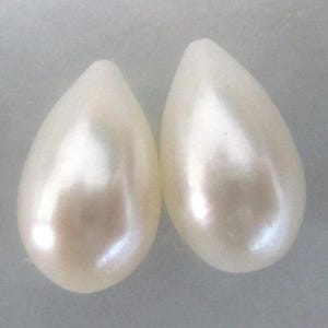 May include: Two pearlescent white teardrop-shaped beads.