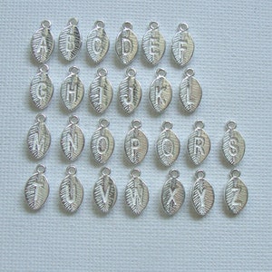 May include: Silver alphabet letter charms in the shape of leaves. Each charm has a different letter of the alphabet, from A to Z.