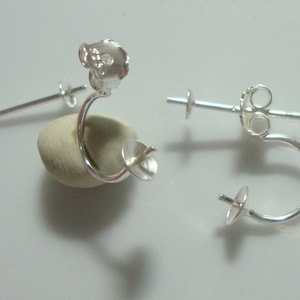 May include: Two silver earring findings with a loop and a post. The findings are designed to hold a gemstone or other embellishment.