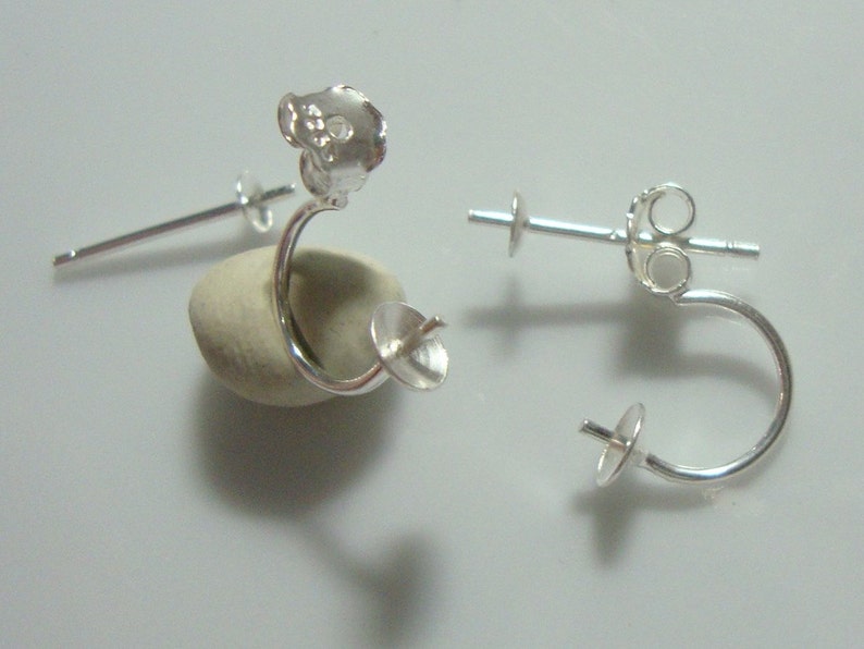 May include: Two silver earring findings with a loop and a post. The findings are designed to hold a gemstone or other embellishment.