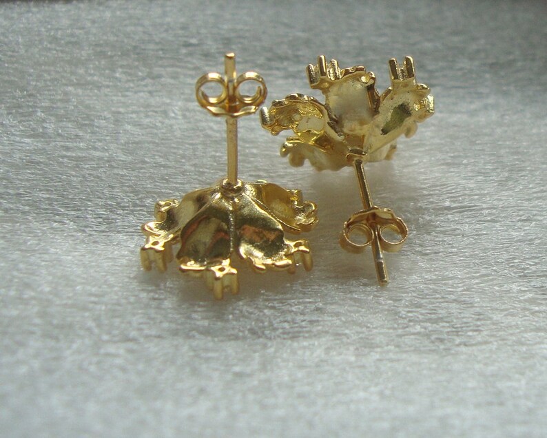 K&ouml;nnte beinhalten: Ein Paar goldfarbene Ohrringe mit einem floralen Design. Die Ohrringe sind aus Metall und haben einen Stiftverschluss.