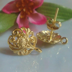 May include: A pair of gold filigree earrings with a floral design. The earrings have a post back closure.
