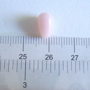 May include: A single, light pink, pearlescent bead measuring approximately 1.2 cm in diameter.