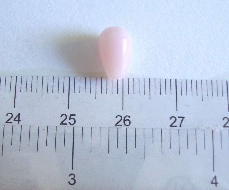 May include: A single, light pink, pearlescent bead measuring approximately 1.2 cm in diameter.