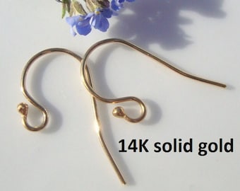 May include: Two 14K solid gold earring hooks. The hooks are gold-colored and have a curved design with a small ball at the end of the hook. The text "14K solid gold" is printed in black.