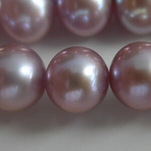 May include: A strand of iridescent pink pearls. The pearls are round and smooth, with a subtle shimmer.