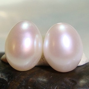 May include: Two round, off-white pearl earrings with a slight iridescent sheen.