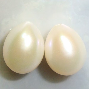 May include: Two white pearlescent oval-shaped beads.