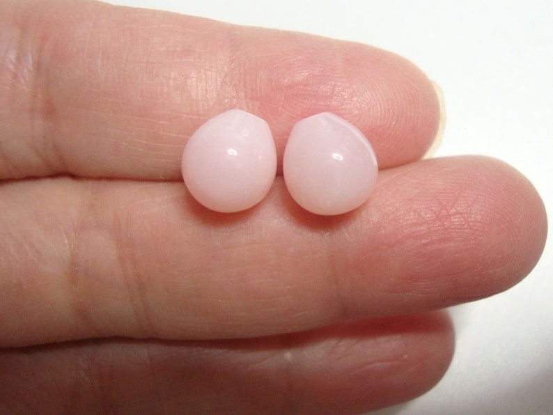 May include: Two pink oval-shaped shell beads.