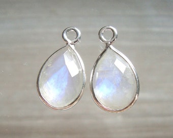 May include: A pair of silver teardrop-shaped pendants with a clear iridescent moonstone gemstone.