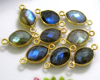 May include: Eight gold-toned oval-shaped labradorite gemstone connector charms with a blue iridescent sheen. Each charm has two jump rings for attaching to jewelry.