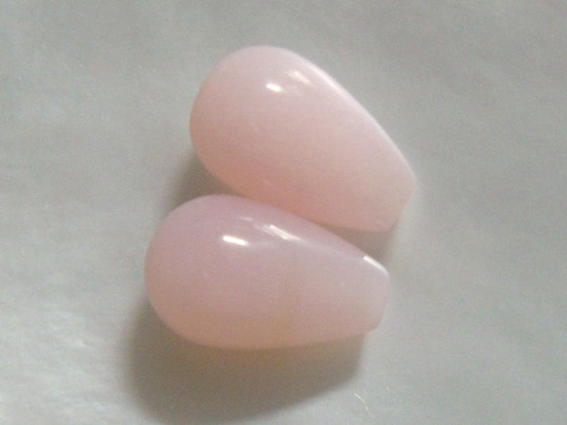 May include: Two teardrop-shaped pink opal stones.