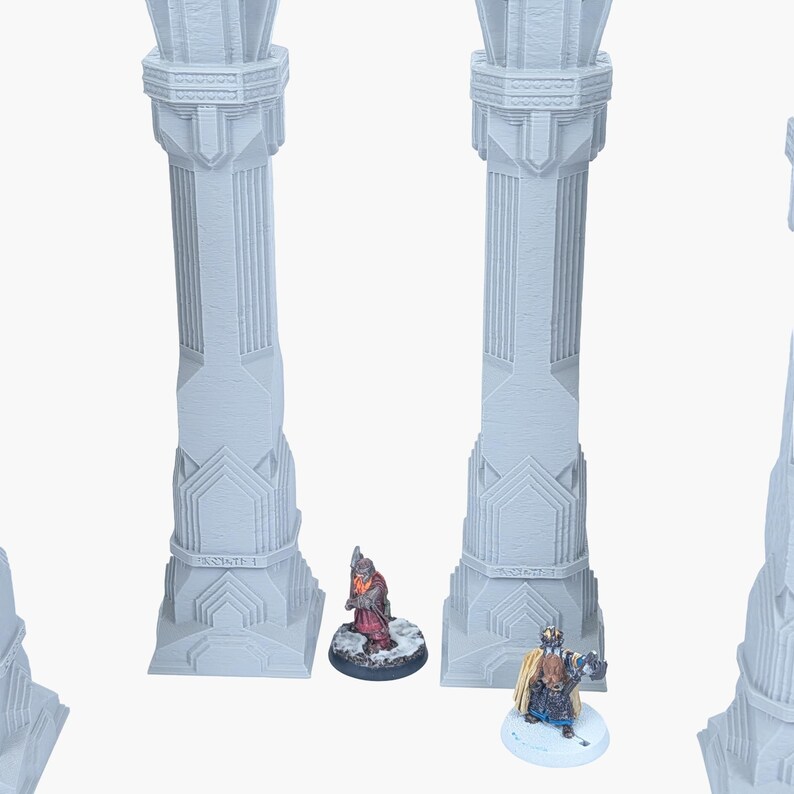 Może przedstawiać: Trzy jasnoszare kolumny architektoniczne ze szczeg&oacute;łowymi geometrycznymi wzorami. Dwie miniaturowe figurki, jedna w kolorze czerwonym, a druga w kolorze niebieskim i złotym, stoją u podstawy kolumn. Kolumny mają napis "INSITATE 1".