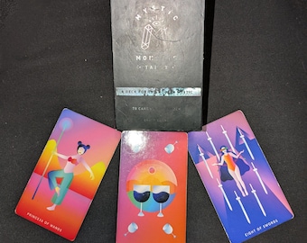 May include: A tarot deck with a black box featuring the text "MYSTIC". Three tarot cards are displayed, including "PRINCESS OF WANDS", "SIX OF CUPS", and "EIGHT OF SWORDS". The cards have colorful illustrations and text.