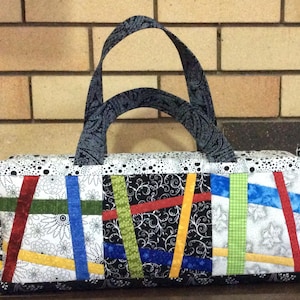 May include: A black and white patchwork tote bag with colorful fabric strips. The bag has a black and white paisley patterned handle.