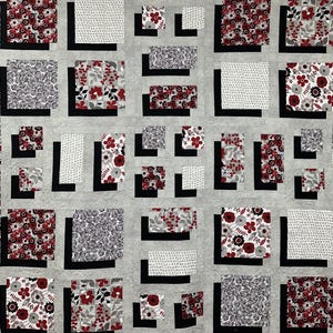 May include: A quilt with a patchwork design featuring black squares with white and red floral patterns. The quilt is made up of various squares with different floral patterns.