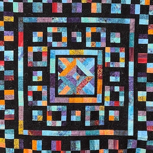 May include: A quilt with a black background and a colourful geometric pattern. The pattern is made up of squares and rectangles in shades of blue, red, orange, and yellow. The quilt is edged with a black border.