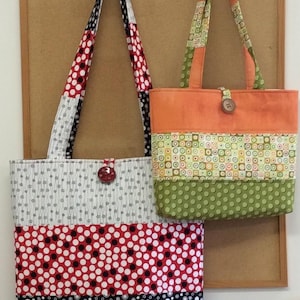 Op de afbeelding: Twee patchwork-tasjes met verschillende patronen. De grotere tas heeft zwart, wit, rood en grijs stof met stippen en cirkels. De kleinere tas heeft oranje, groen en geel stof met geometrische patronen.