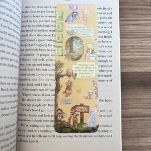 Puede incluir: Un marcapáginas temático de Winnie the Pooh con ilustraciones de Pooh, Piglet, Tigger y Eeyore. El marcapáginas tiene la palabra "POOH" verticalmente, con el letrero del Bosque de los Cien Acres y citas.