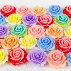 May include: Assortment of colorful glittery rose-shaped embellishments. The roses are in shades of pink, red, orange, yellow, green, blue, and purple.