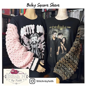Peut inclure: Deux t-shirts noirs avec des manches originales. L'un présente une manche rose crochetée et un motif Betty Boop. L'autre a une manche texturée marron et noire et un motif "Twilight Saga". Le logo de la boutique est visible.