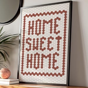 May include: A framed print with a white background and a red hexagonal tile pattern that spells out "Home Sweet Home".