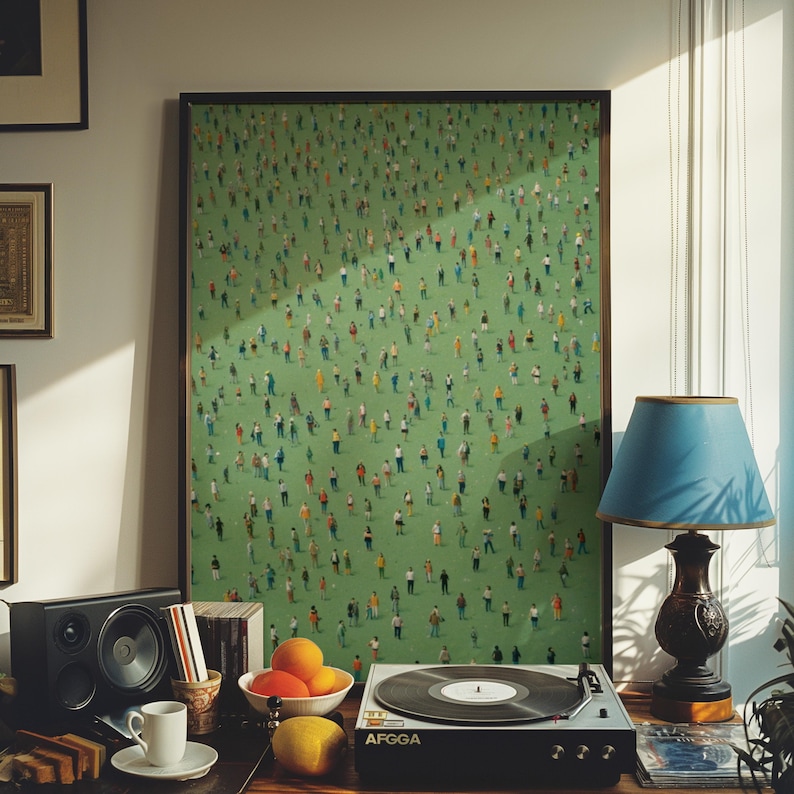 May include: A framed painting of a green field with hundreds of tiny people in various colors and poses. The painting is hanging on a wall above a record player and a lamp.