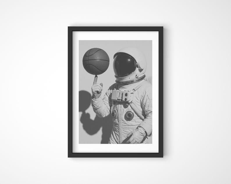 Black and white photograph of an astronaut spinning a basketball on their finger poster print wall art