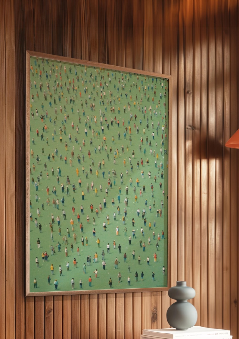 May include: A framed print of a green field with hundreds of tiny people in various colors and poses. The print is hanging on a wood panel wall.